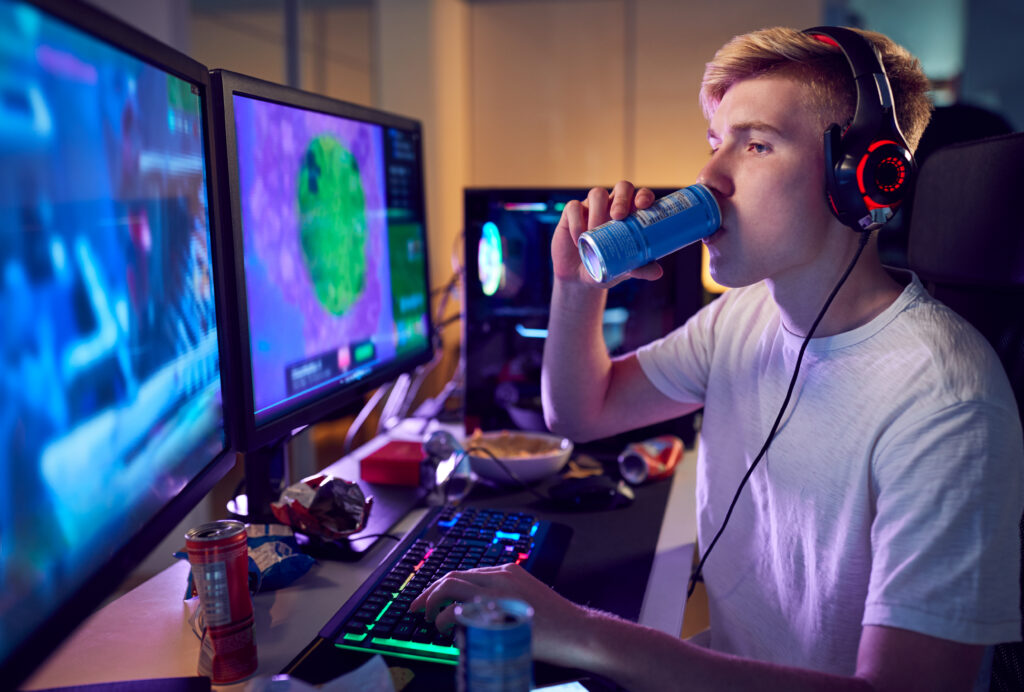 Teenager-Junge spielt Videospiel und trinkt ein Energy-Drink.